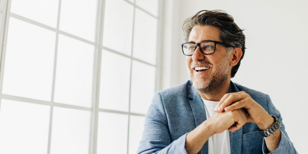 Business man looking outside the window in an office smiling