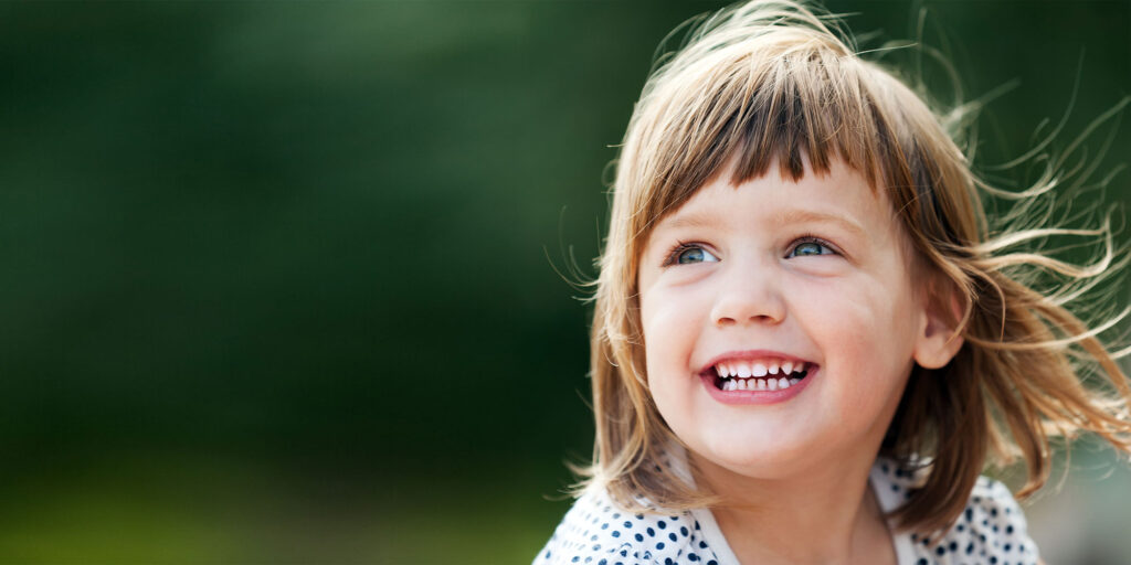 young child smiling brightly while being outside