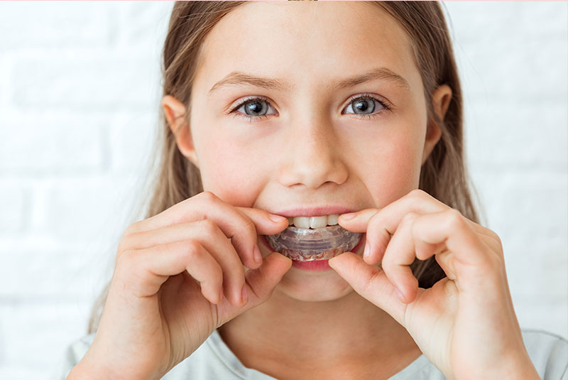 close up of young female child putting in their molded plate for dental care