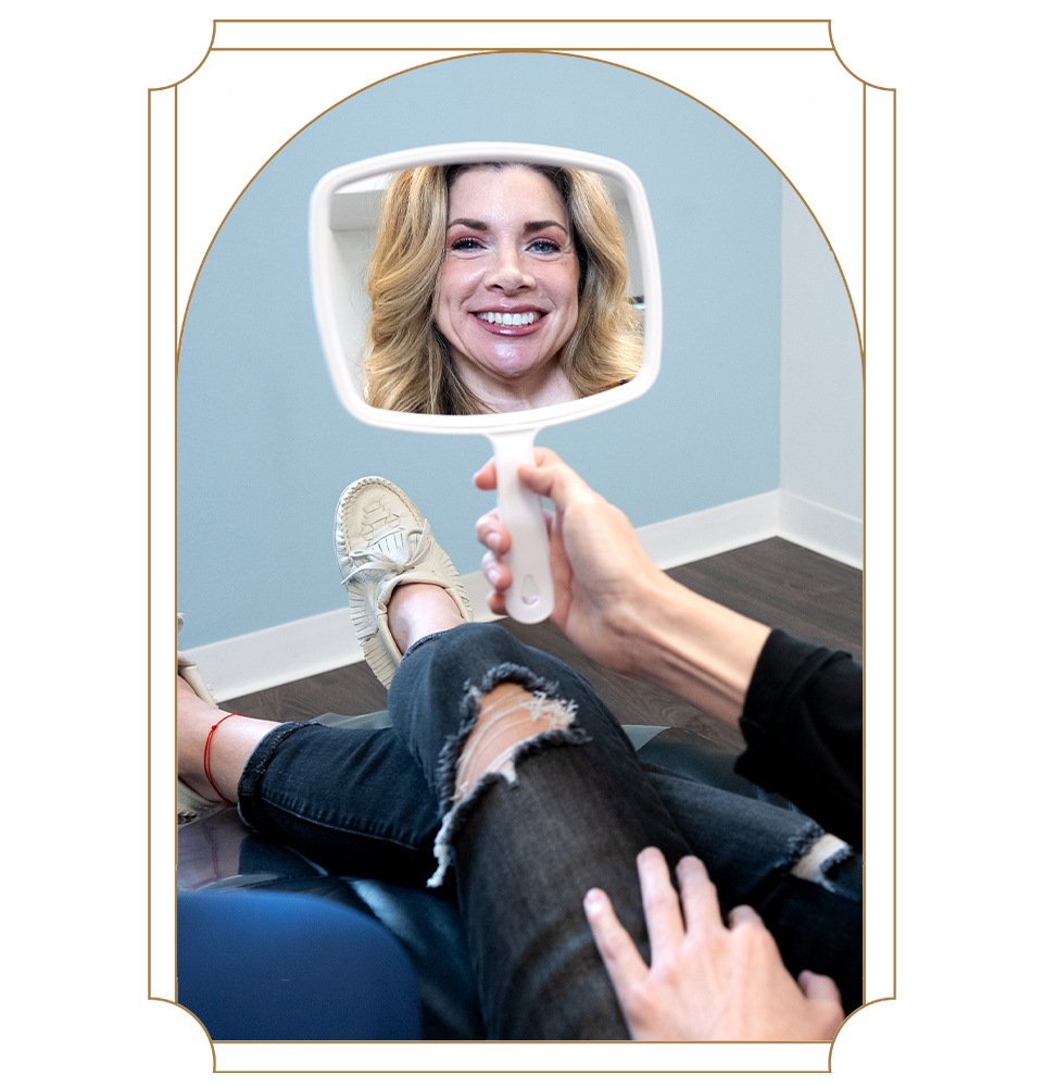 patient looking into mirror after veneers to see their new smile